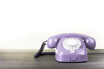 Fototapete - Retro violet telephone on table against white background