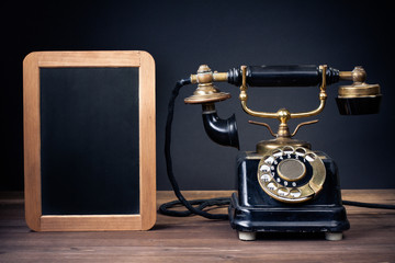 Fototapete - Vintage old telephone, black board frame on wood table