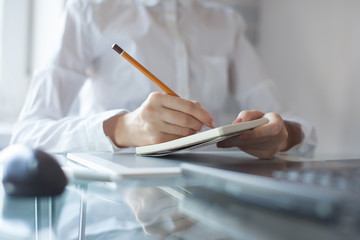 Woman's hand using a pencil noting on notepad