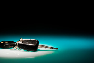 Car keys on blue, reflective table and black background