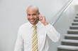 © lightwavemedia - Smiling businessman using cellphone against staircase
