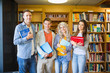 © WavebreakmediaMicro - Students with folders against bookshelf in library