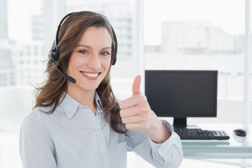 Wall Mural - Businesswoman wearing headset while gesturing thumbs up in offic