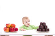 © StefanieBaum - Kleiner Bub hat die Wahl zwischen Obst und Süssigkeiten