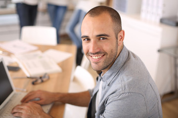 Aufkleber - Smiling young man in office working on laptop