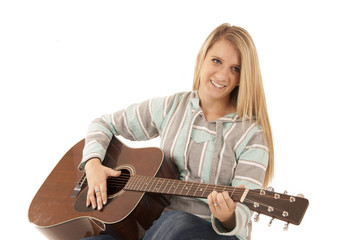 Young blonde woman playing acoustic guitar