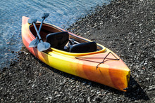Orange And Yellow Kayak With Oars On The Sea Shore