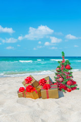 Canvas Print - Christmas tree and golden gift with big red bow on the sea beach