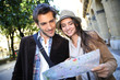 © goodluz - Couple of tourists walking in town with map and tablet