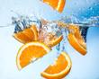 Orange fruits fall deeply under water with a big splash