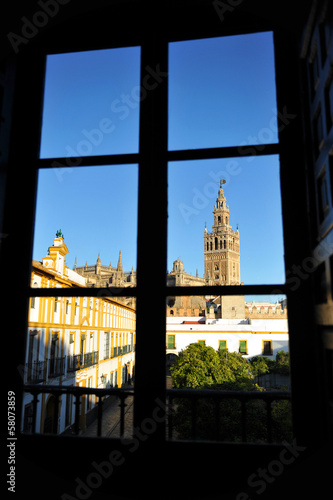 Board z aluminiowym obramowaniem Wieża Giralda przez okno, Sewilla, Hiszpania