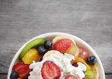 Sweet tasty fruit salad in the bowl with whipped cream