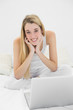 © lightwavemedia - Content blonde woman smiling at camera while using her notebook