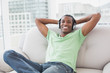 © lightwavemedia - Relaxed young Afro man with headphones sitting on sofa