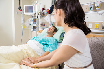 Woman Holding Man's Hand Lying On Bed