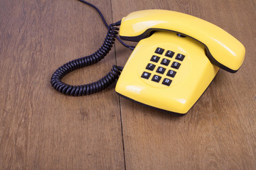 Fototapete - Retro yellow telephone on old wooden table background