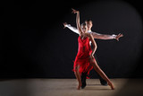 Fototapeta Big Ben - Latino dancers in ballroom against black background