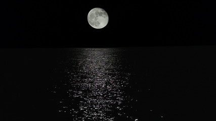 moonlight path with low fool moon above the sea