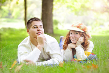 Young beautiful couple on green grass in autumn