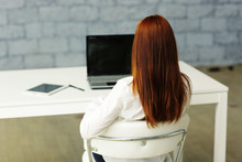 Picture From Behind Of A Businesswoman Sitting At Her Desk