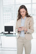 © lightwavemedia - Elegant businesswoman text messaging in a bright office
