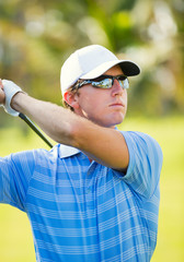 Wall Mural - Young man swinging golf club