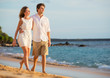 © EpicStockMedia - Romantic happy couple walking on beach at sunset. Smiling holdin