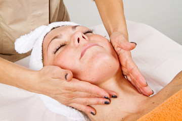 Beautiful young woman receiving facial massage with closed eyes