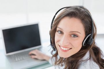 Wall Mural - Smiling businesswoman wearing headset in front of laptop