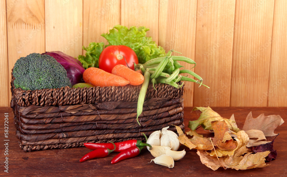 Different vegetables in basket with yellow leaves
