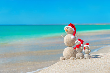 Wall Mural - Snowmans family at sea beach in santa hat. New years and christm