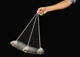 Fototapeta Konie - Close-up of a person's hand swinging a stone pendulum