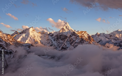 Obraz na płótnie canvas Ama dablam szczyt (6856 m) nad chmurami w łagodnym wieczornym świetle.