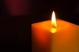 Fototapeta  - The yellow candle burning in the dark