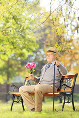 Poster - Senior gentleman with bouquet of flowers sitting on a bench, in