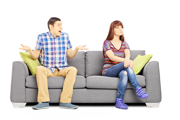 Poster - Young couple sitting on a couch during an argument