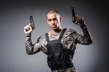 Soldier with guns against dark background