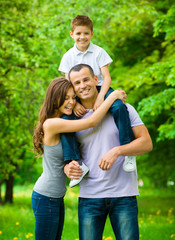 Happy family of three. Father keeps son on shoulders