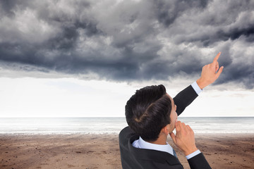 Poster - Composite image of thoughtful asian businessman pointing
