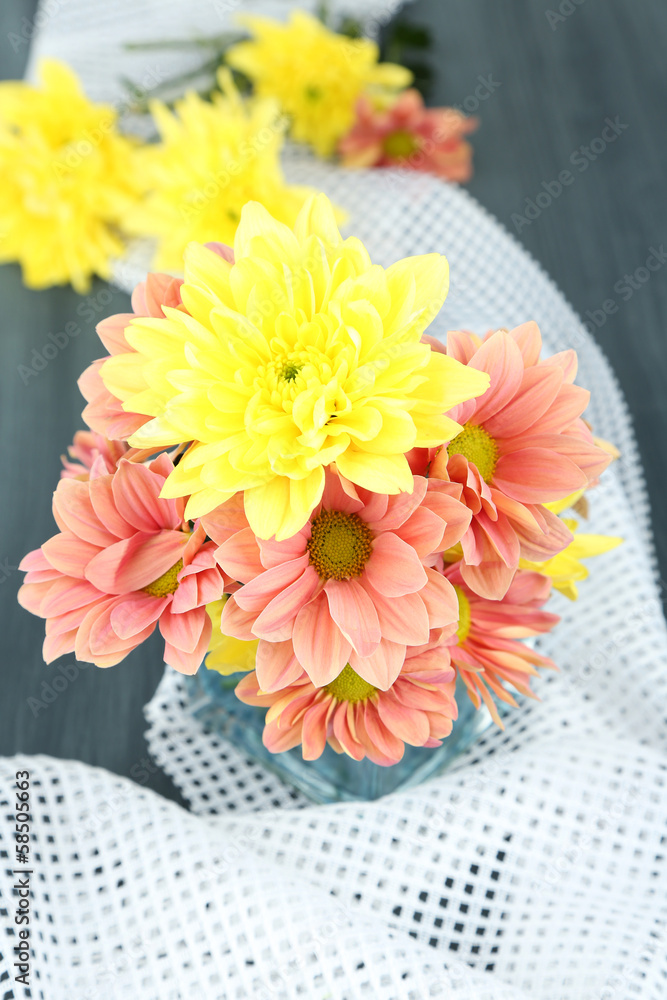 Chrysanthemum flowers in vase on wooden table close-up