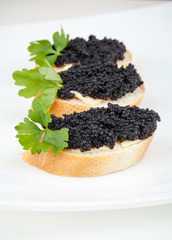 Wall Mural - Small sandwiches with black caviar on white plate