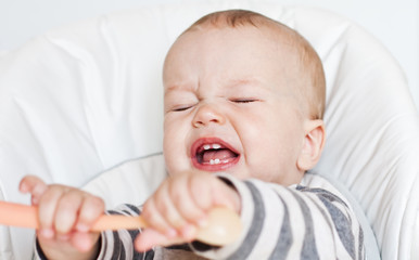 cute little boy crying holding a spoon