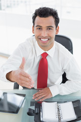 Wall Mural - Businessman offering a handshake at office desk