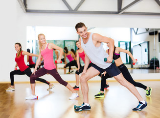 Poster - group of smiling people working out with dumbbells