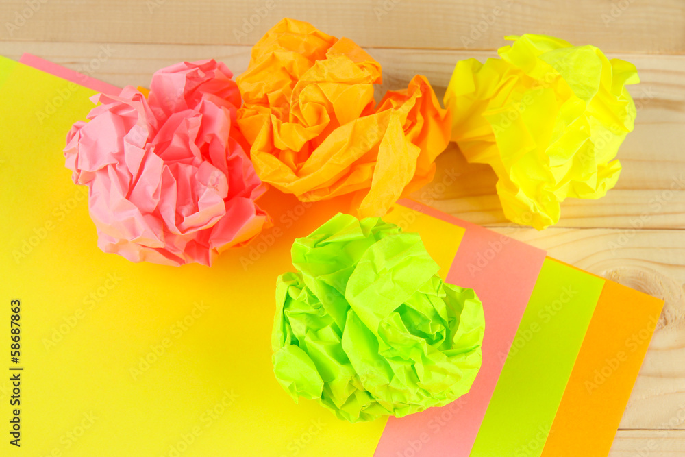 Colorful crumpled paper balls on wooden background