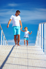 happy father and son walking on blue sky horizon