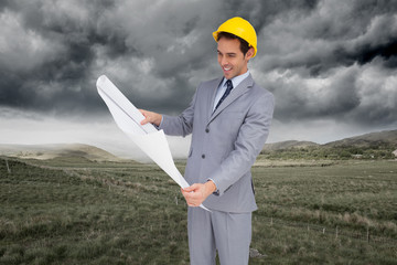 Wall Mural - Composite image of smiling architect with hard hat looking at pl