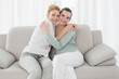 © lightwavemedia - Cheerful young female friends embracing in living room