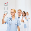 © Syda Productions - doctor or nurse drawing checkmark into checkbox
