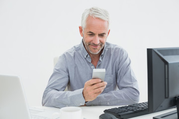 Businessman with cellphone, laptop and computer at desk